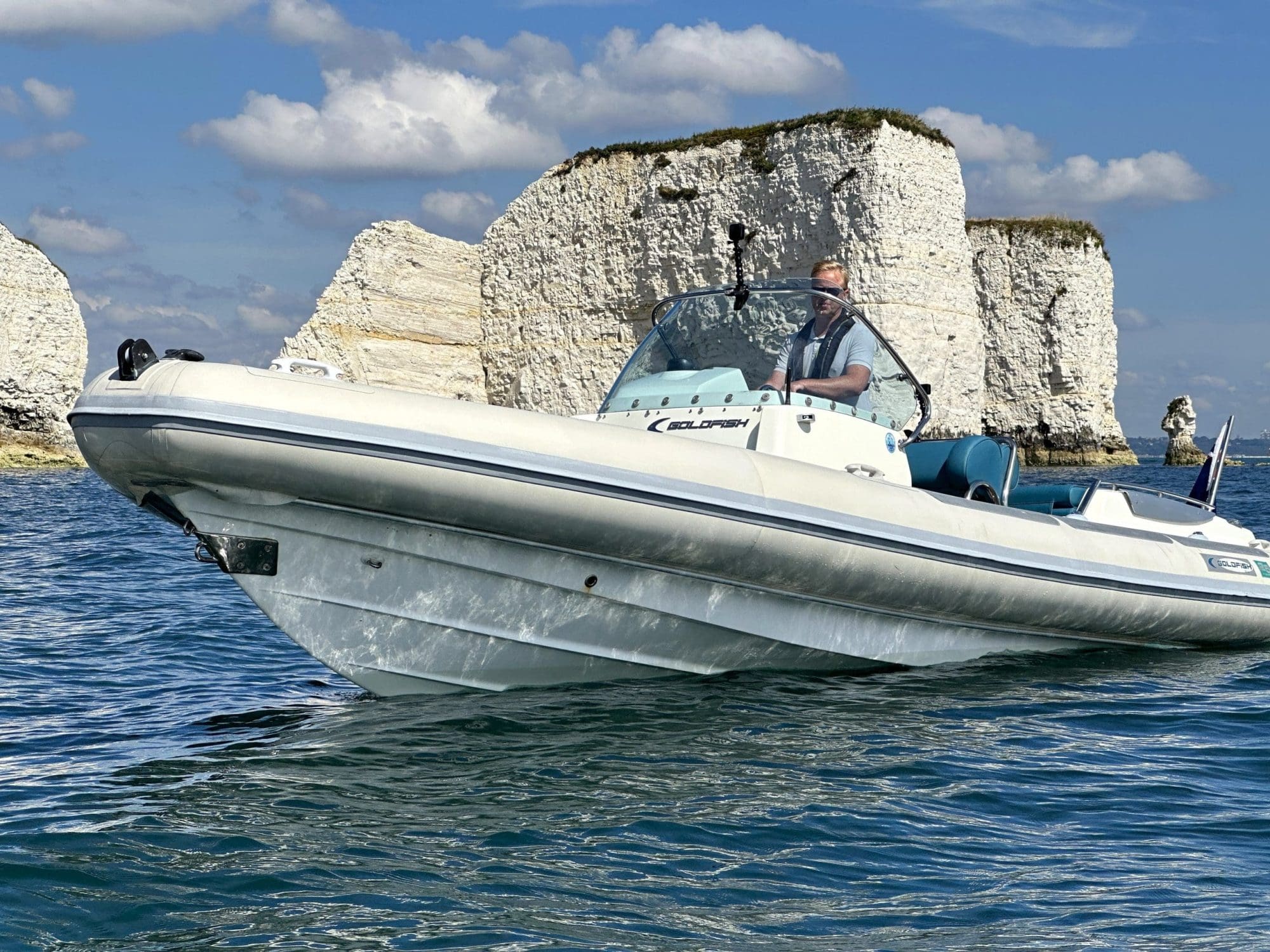 Boats for sale Weymouth - A Goldfish RIB boat cruising in clear waters near the iconic white cliffs, showcasing the thrill and adventure of owning a boat in the Weymouth area.